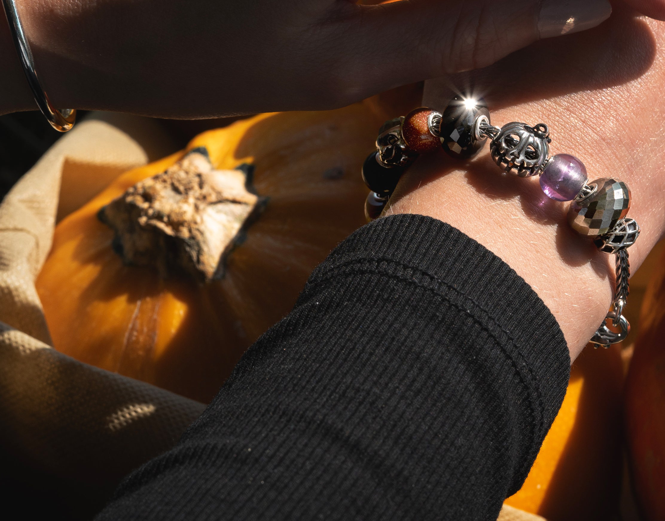 Trollbeads model wearing a halloween style pumpkin bead on a bracelet while holding a pumpkin n a bag